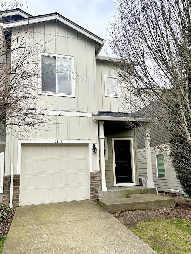 view of front of house featuring board and batten siding, stone siding, driveway, and an attached garage