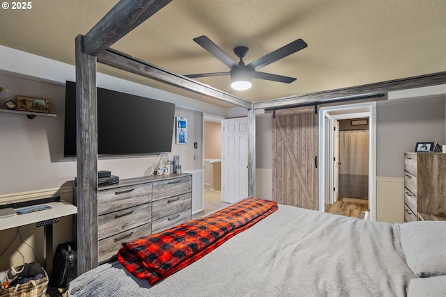 816 SW Chablis Ct, Dundee, OR 97115 - bedroom with a textured ceiling, a barn door, ceiling fan, ensuite bathroom, and a wainscoted wall