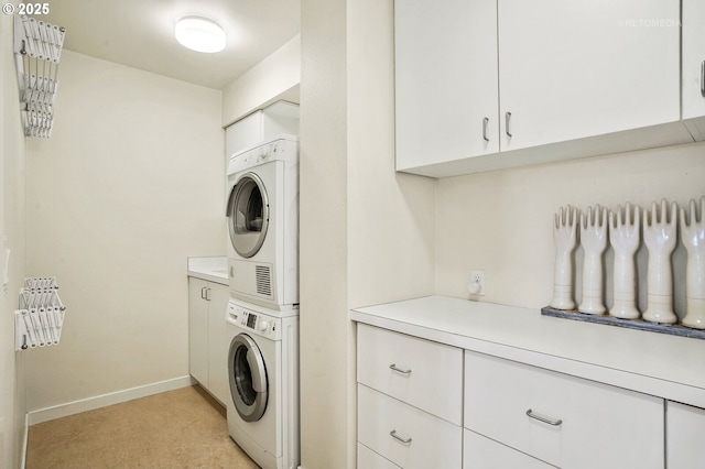 laundry room featuring stacked washer / dryer, cabinet space, and baseboards