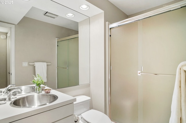 bathroom with a stall shower, toilet, vanity, and recessed lighting