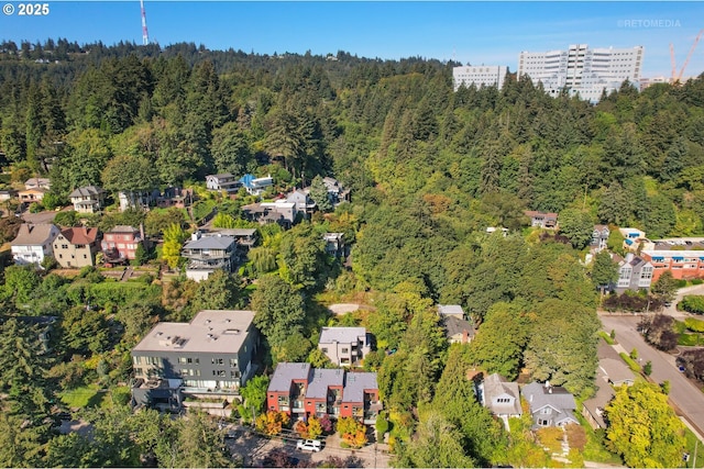 aerial overview of property's location featuring a forest and nearby suburban area