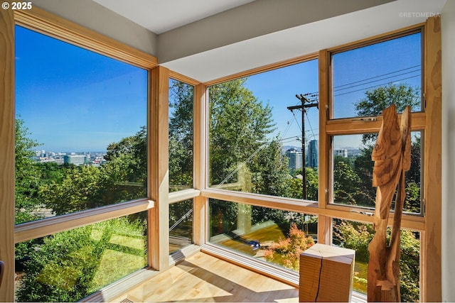 unfurnished sunroom featuring a city view and wood finished floors