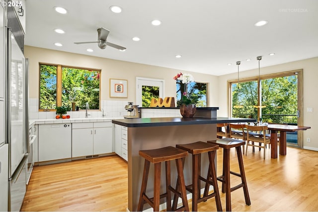 kitchen with recessed lighting, a peninsula, light wood-style flooring, ceiling fan, and a breakfast bar area