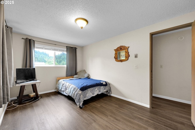 bedroom featuring wood finished floors, a textured ceiling, and baseboards