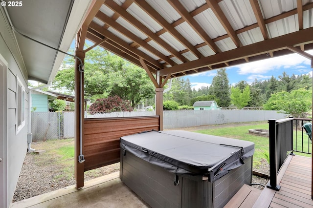 wooden terrace with a hot tub, a fenced backyard, view of wooded area, and a patio area