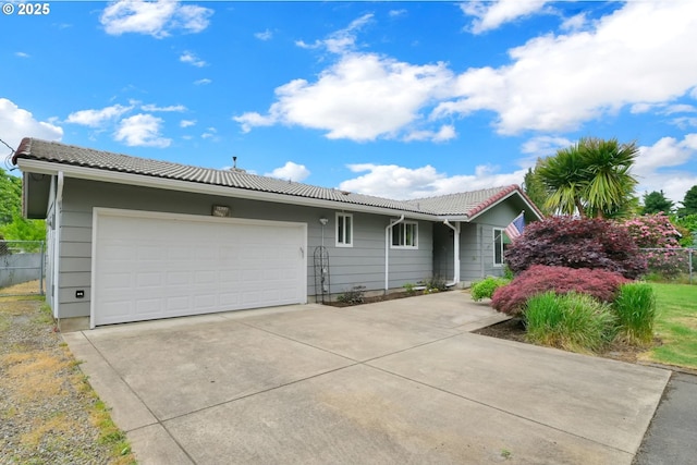 ranch-style house featuring a tiled roof, fence, an attached garage, and driveway