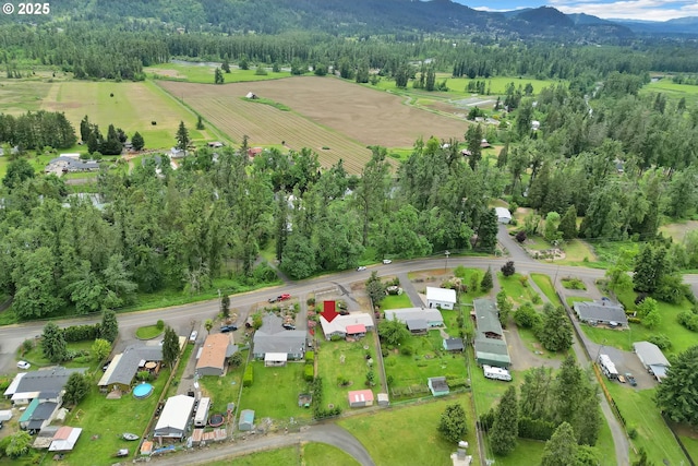 aerial view of property and surrounding area featuring a mountain backdrop, rural landscape, and a heavily wooded area