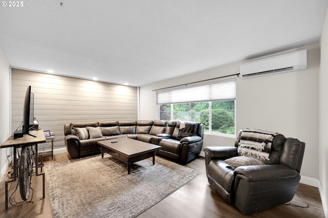 living room with a wall mounted AC, wood finished floors, and baseboards