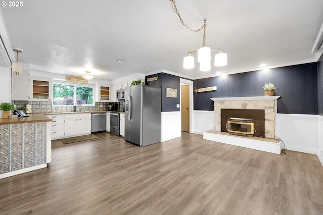 kitchen with appliances with stainless steel finishes, dark wood-style flooring, open floor plan, white cabinetry, and decorative backsplash