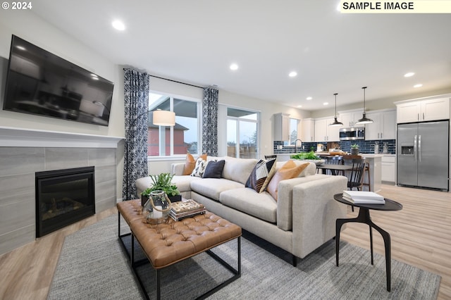 living room with sink, light hardwood / wood-style floors, and a tile fireplace