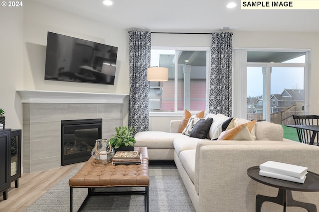 living room featuring a tiled fireplace and light hardwood / wood-style floors