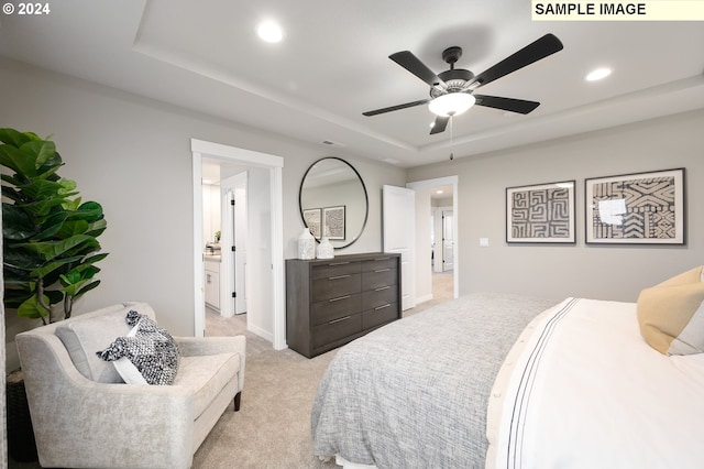 carpeted bedroom featuring a tray ceiling, ceiling fan, and ensuite bathroom