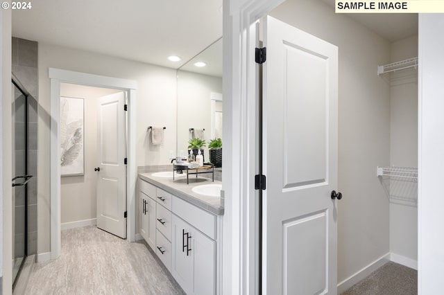 bathroom featuring hardwood / wood-style flooring, vanity, and a shower with door