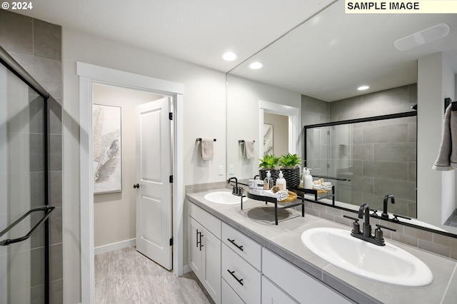 bathroom with wood-type flooring, a shower with door, and vanity