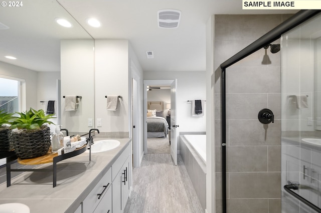 bathroom with hardwood / wood-style flooring, vanity, and plus walk in shower