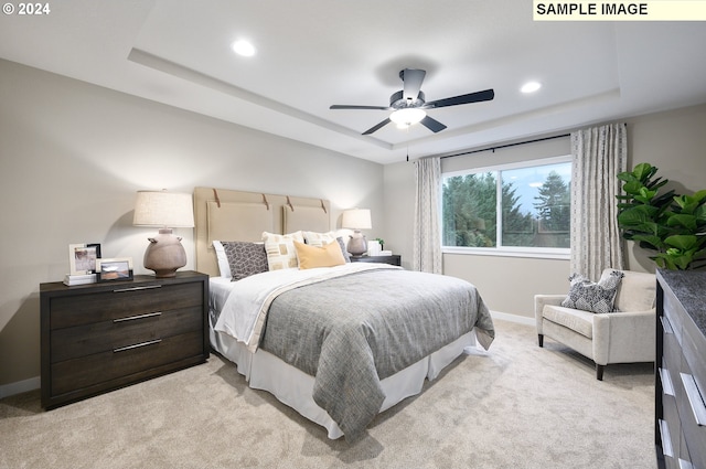 bedroom with ceiling fan, a raised ceiling, and light carpet