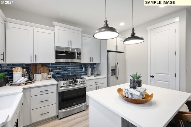 kitchen featuring pendant lighting, white cabinetry, stainless steel appliances, a kitchen island, and decorative backsplash