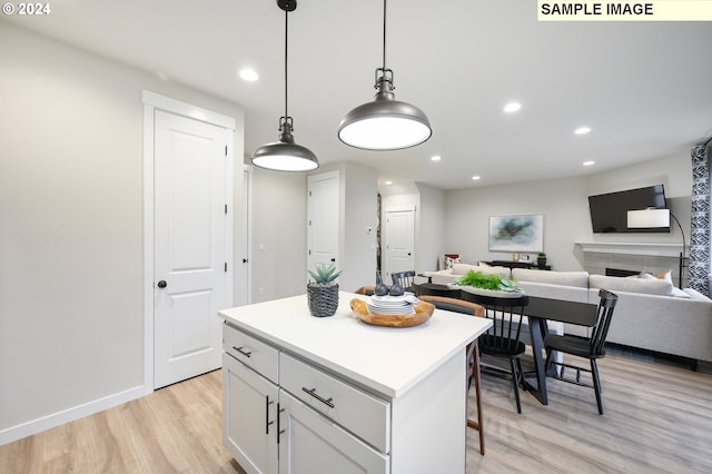 kitchen featuring pendant lighting, a kitchen breakfast bar, a center island, white cabinets, and light wood-type flooring