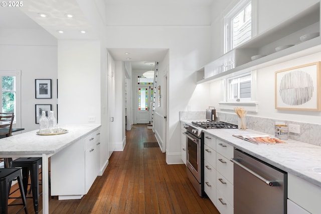 1720 NW Hoyt St, Portland, OR 97209 - kitchen featuring stainless steel appliances, white cabinetry, healthy amount of natural light, dark wood-style flooring, and recessed lighting
