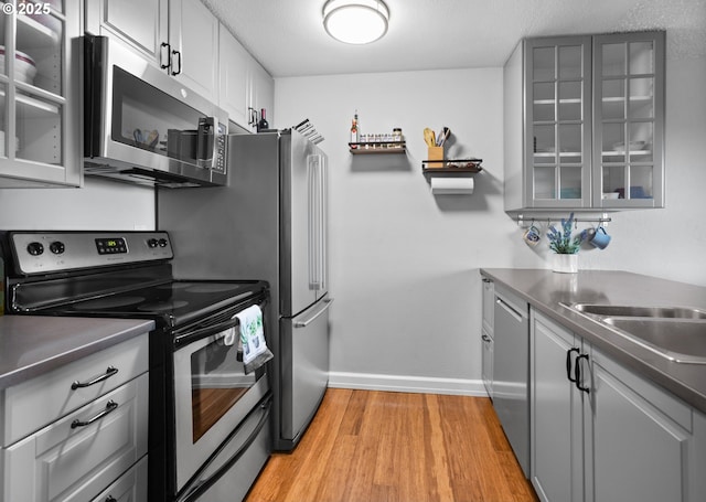 kitchen with sink, gray cabinets, stainless steel appliances, and light wood-type flooring