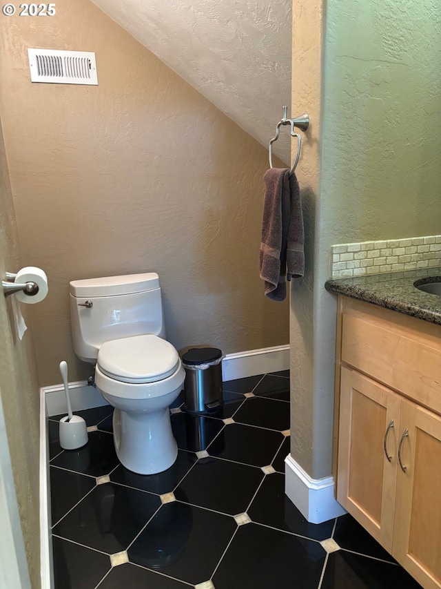 34103 Adler Ln, Creswell, OR 97426 - half bathroom featuring toilet, vaulted ceiling, vanity, a textured wall, and baseboards
