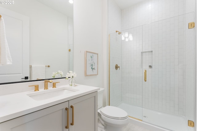 bathroom featuring vanity, a shower with shower door, and toilet