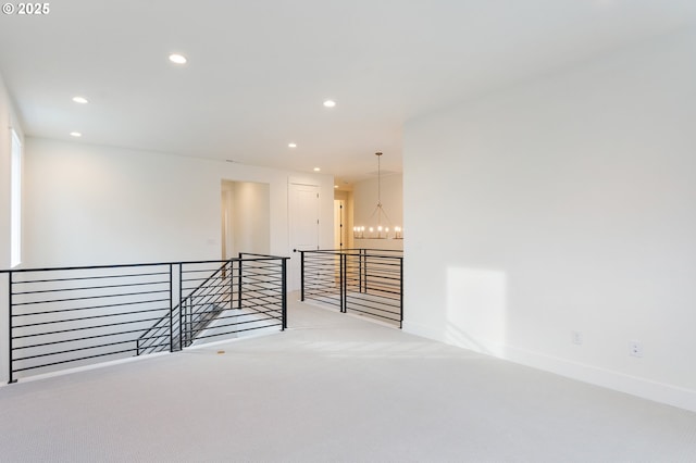 carpeted spare room featuring recessed lighting, baseboards, and a notable chandelier