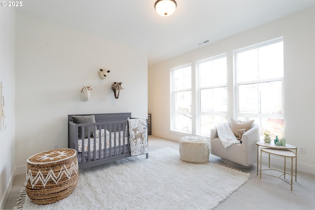 carpeted bedroom with visible vents, baseboards, and a nursery area