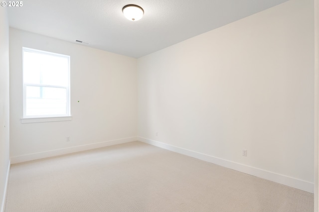 spare room with visible vents, light colored carpet, and baseboards