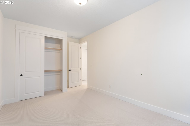 unfurnished bedroom with baseboards, a closet, and light carpet