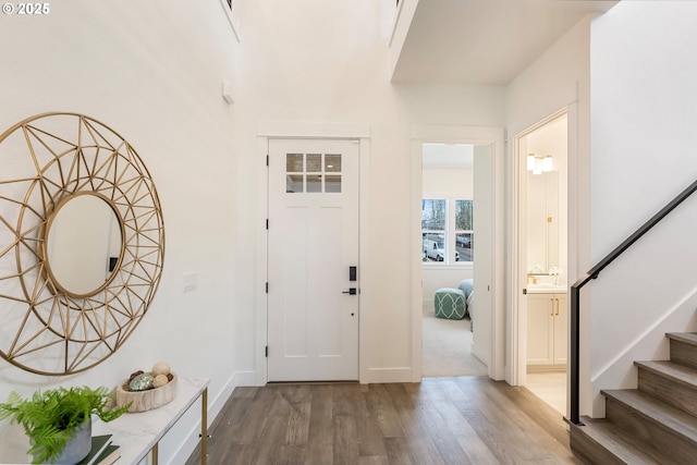 foyer entrance featuring baseboards, wood finished floors, and stairs