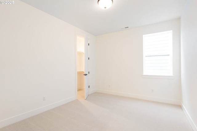 unfurnished room featuring visible vents, baseboards, and light colored carpet