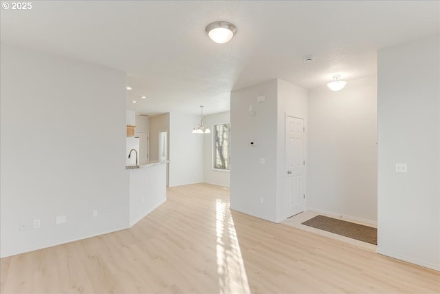 empty room featuring an inviting chandelier, a textured ceiling, and light hardwood / wood-style floors