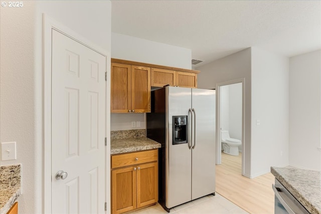 kitchen with stainless steel appliances, light tile patterned floors, and light stone counters