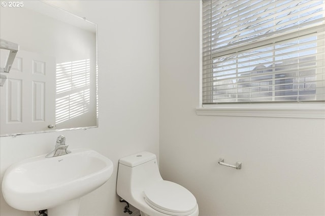 bathroom with plenty of natural light, toilet, and sink