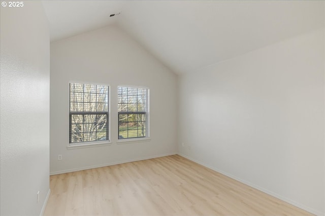 empty room with vaulted ceiling and light hardwood / wood-style floors