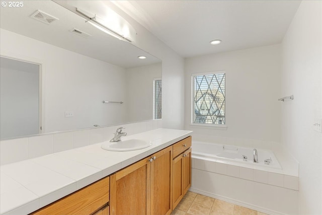 bathroom with vanity, tile patterned flooring, and tiled tub