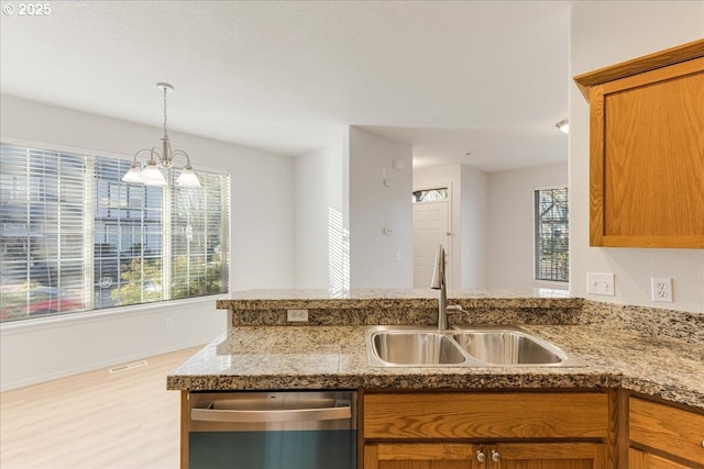 kitchen featuring a wealth of natural light, sink, stainless steel dishwasher, and an inviting chandelier