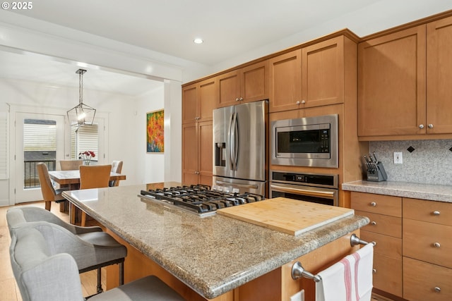 kitchen featuring backsplash, brown cabinets, appliances with stainless steel finishes, and a kitchen island