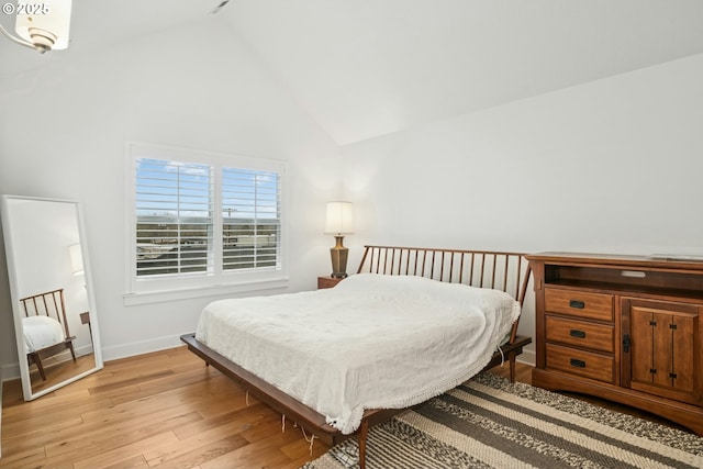 bedroom with high vaulted ceiling, light wood-type flooring, and baseboards