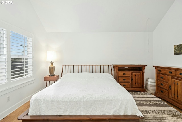 bedroom featuring baseboards, lofted ceiling, and wood finished floors