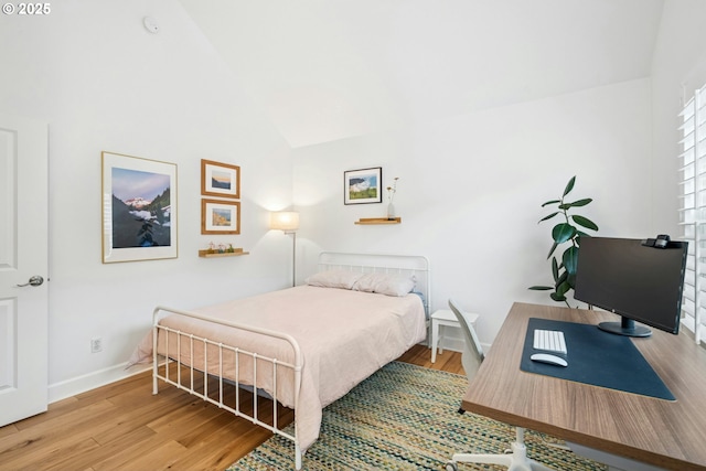 bedroom featuring baseboards, lofted ceiling, and wood finished floors