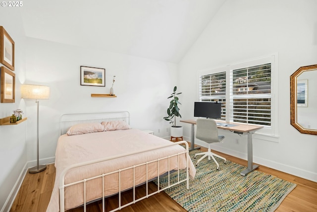 bedroom featuring baseboards, high vaulted ceiling, and wood finished floors