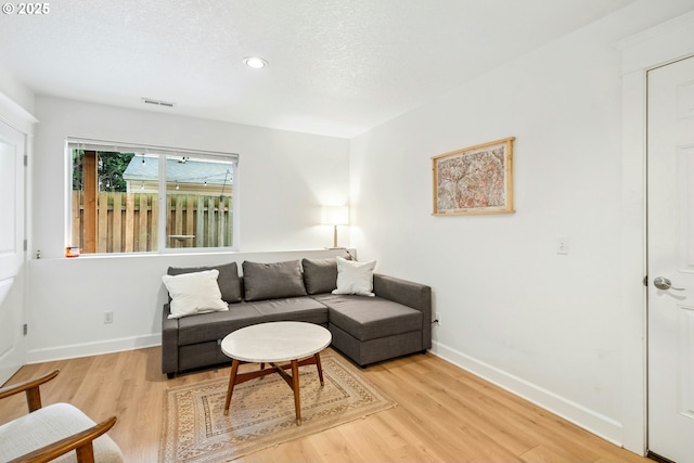 living area with visible vents, light wood-style flooring, a textured ceiling, recessed lighting, and baseboards