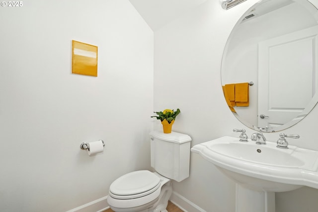 bathroom featuring toilet, visible vents, baseboards, and a sink