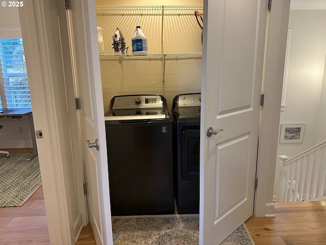 clothes washing area featuring laundry area, independent washer and dryer, and wood finished floors