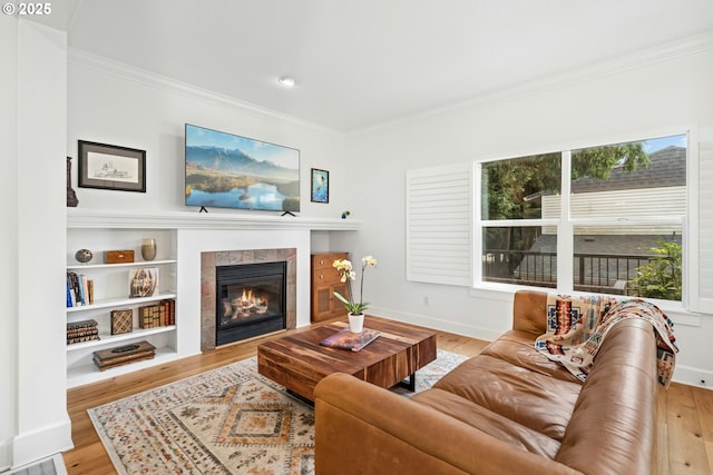 living room with baseboards, wood finished floors, crown molding, and a tile fireplace