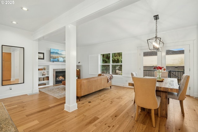 dining space with light wood finished floors, crown molding, baseboards, a tiled fireplace, and recessed lighting