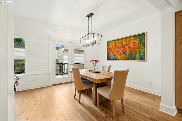 dining area with crown molding, a notable chandelier, light wood-style floors, and baseboards