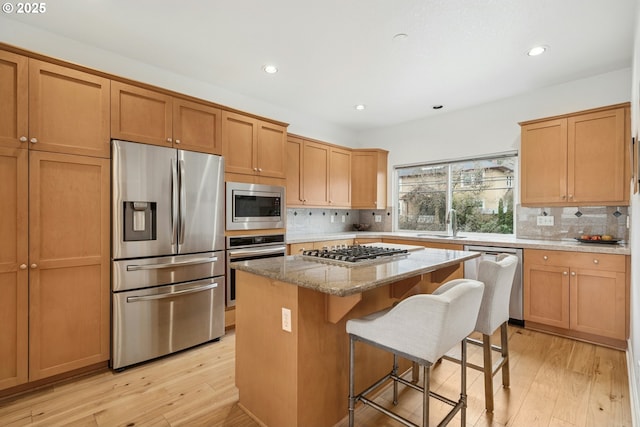 kitchen featuring a center island, stainless steel appliances, light wood-style floors, and a sink